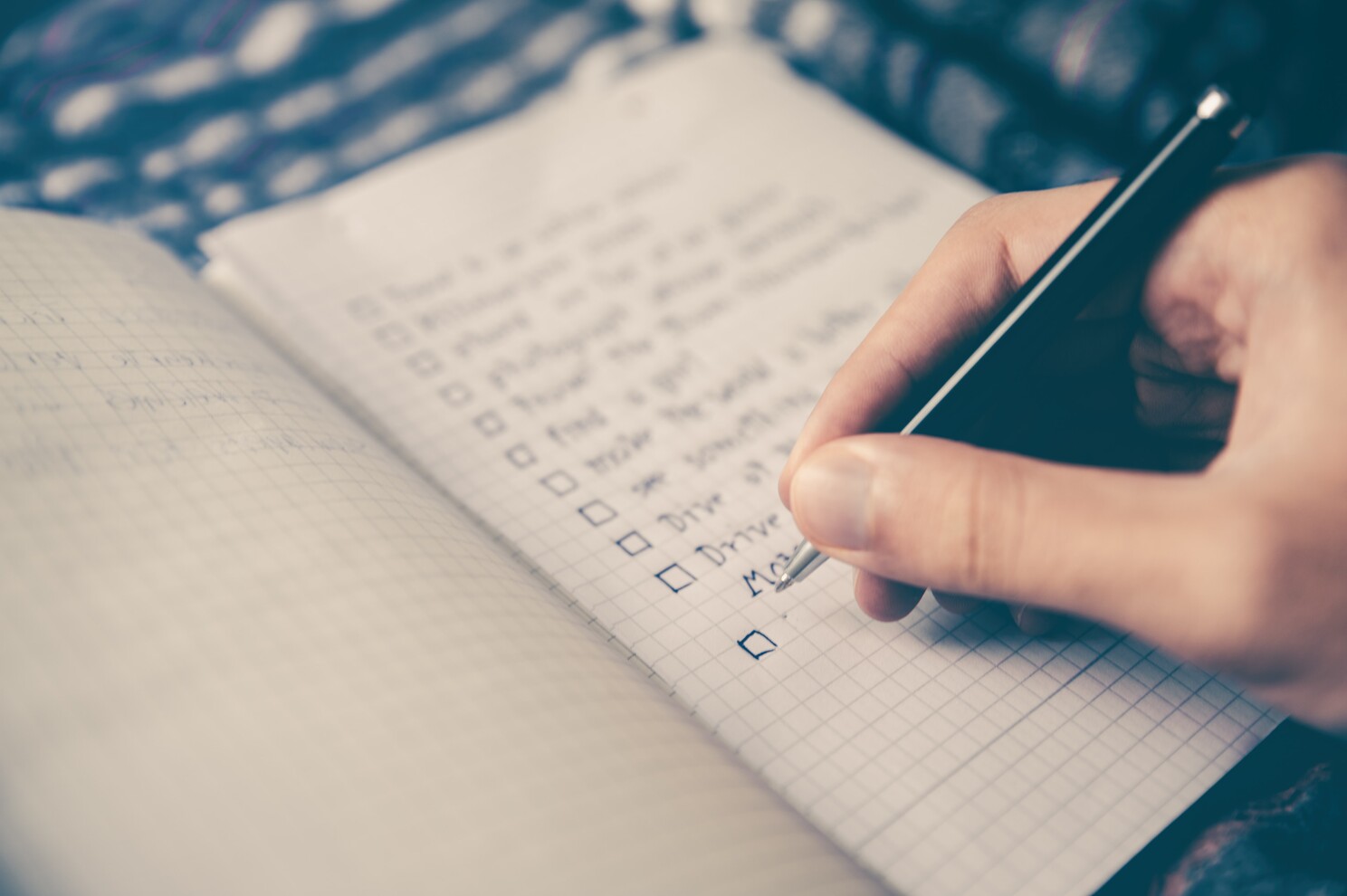 man writing a to do list on a notebook